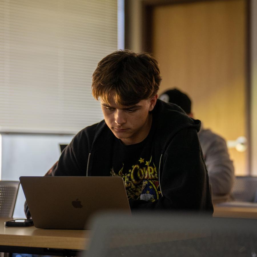 male student in class on a computer working